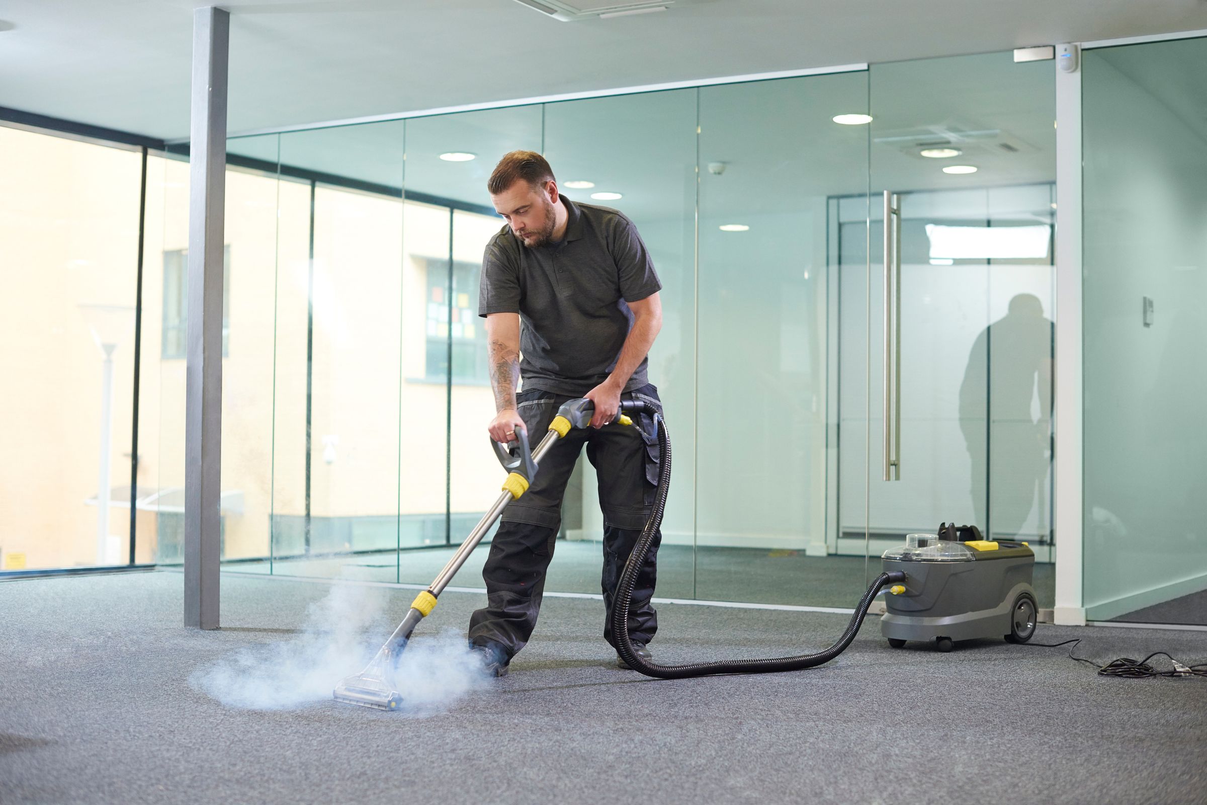 A man cleans a carpet with a vacuum cleaner, representing a Miami, FL mold removal service.