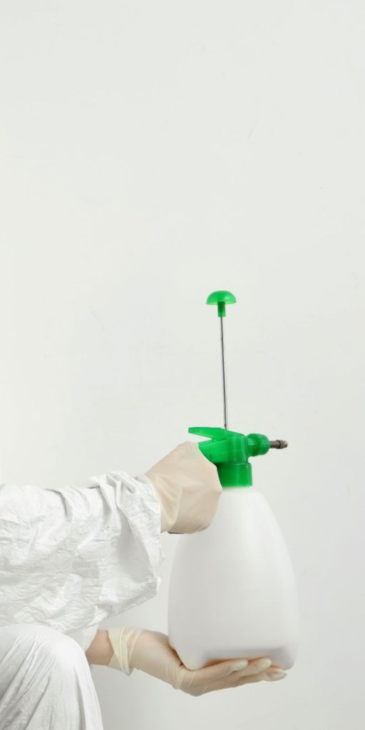 A person in a white coat holds a spray bottle, representing a mold removal service in Miami, FL.